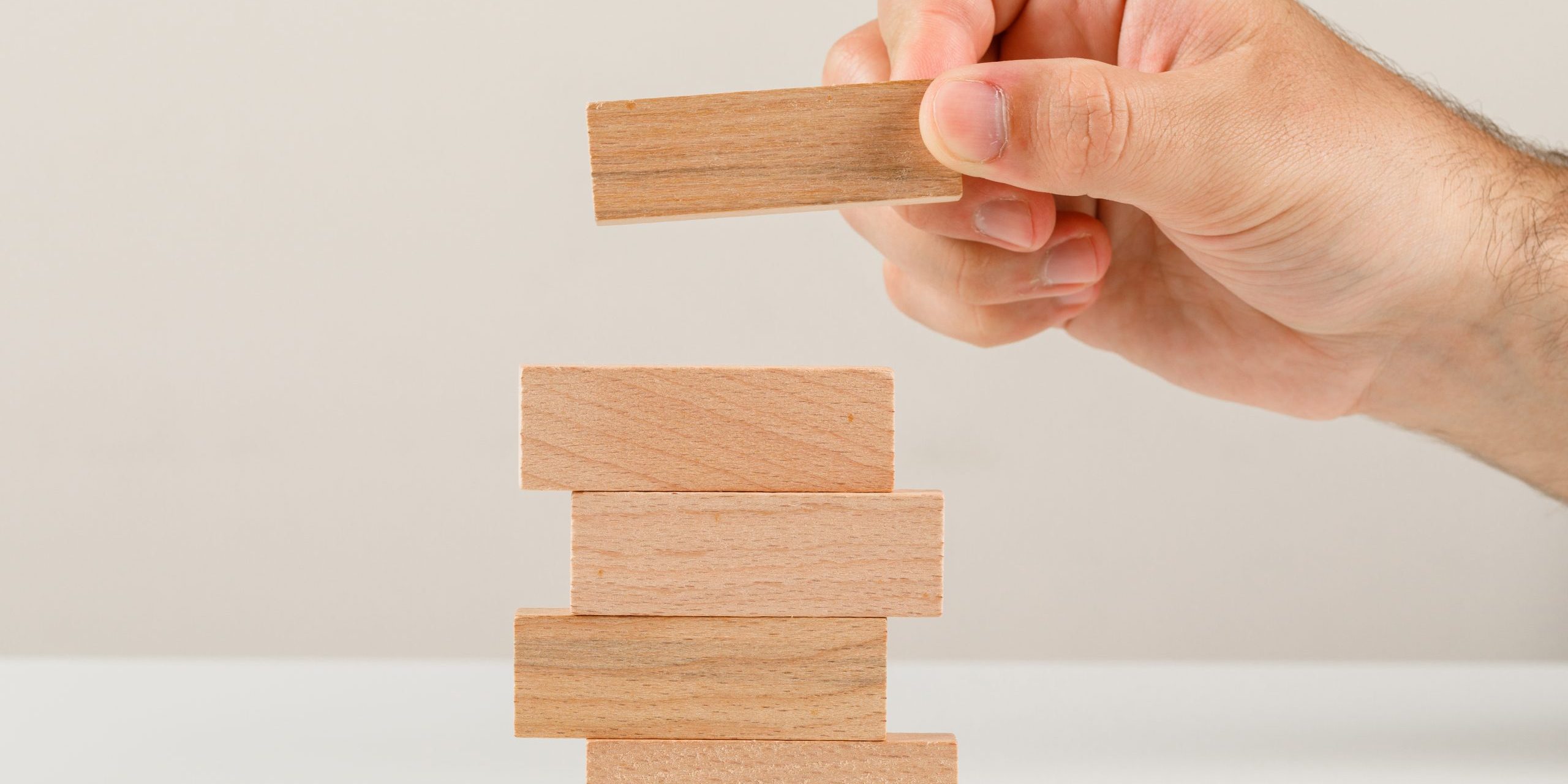 Business planning concept on white backgroud side view. hand placing wooden block on tower.